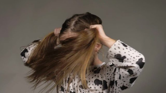 Happy little girl in the studio on a gray background. She jumps, shows different emotions. Hair fluttering from the wind. Super slow motion, shot at 180fps.
