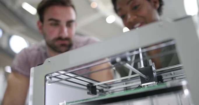 Closeup of colleagues looking at a 3D printer