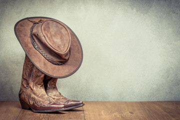 Wild West retro leather cowboy hat and old boots front concrete wall background. Vintage instagram...