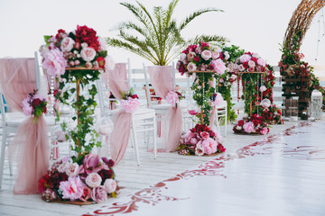 Beautiful decoration of the wedding ceremony in pink, burgundy and white tones on wooden pier....