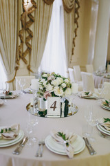 Beautiful decoration of a wedding banquet in a restaurant in pastel colors. Decoration of banquet dinner table vase with flower arrangement, candlestick, card with number of table in frame