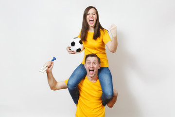 Inspired young couple, woman sit on man shoulders, fans with soccer ball pipe cheer favorite...