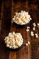 Still life on a wooden background with two bowls of popcorn.