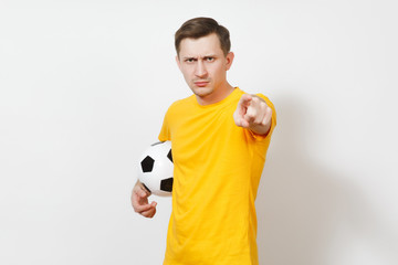 Young angry European man, fan or player in yellow uniform hold soccer ball point index finger camera cheer favorite football team isolated on white background. Sport, play football, lifestyle concept.
