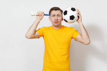 Inspired young fun cheerful European man, fan or player in yellow uniform hold soccer ball, pipe, cheer favorite football team isolated on white background. Sport, play football, lifestyle concept.