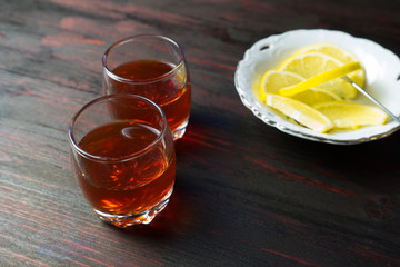 A glass of alcohol and sliced lemon.