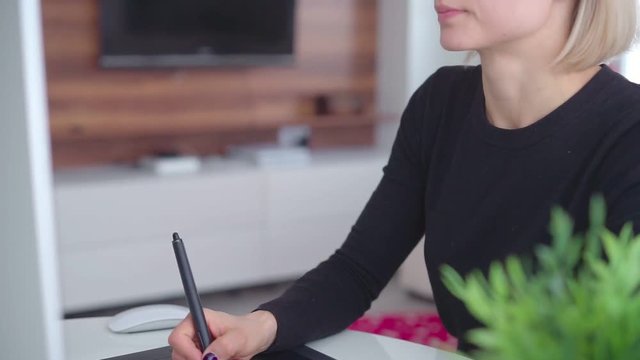 Female use a graphic tablet and stylus to work behind a modern computer screen. Young girl working distance