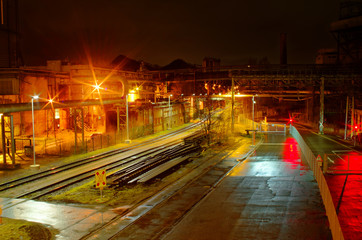 Fototapeta premium Industriebahnhof Rangierbahnhof bei Nacht mit vielen Lichtern und Waggons auf einem Abstellgleis in einer Industrieanlage mit violetter Optik
