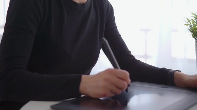 Female use a graphic tablet and stylus to work behind a modern computer screen. Young girl working distance