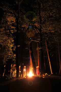 People Gathered Around A Fire At Nights In The Woods