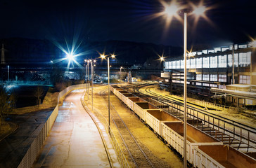 Fototapeta na wymiar Industriebahnhof Rangierbahnhof bei Nacht mit vielen Lichtern und Waggons auf einem Abstellgleis in einer Industrieanlage mit violetter Optik