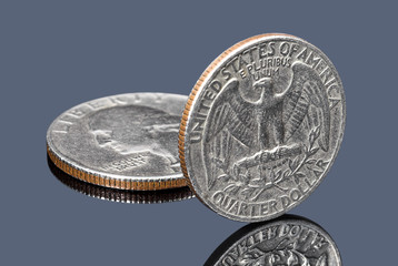 Quarter dollar coins on dark mirror surface