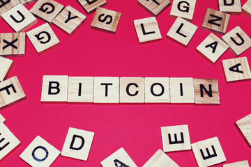 Wooden blocks on a red background spelling words Bitcoin