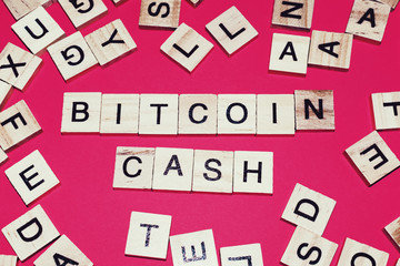 Wooden blocks on a red background spelling words Bitcoin Cash