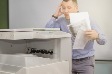 a young office manager wonders or is surprised at the work of a multifunction printer or copier