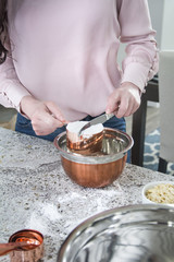 woman cooks and bakes in kitchen with copper bowls 