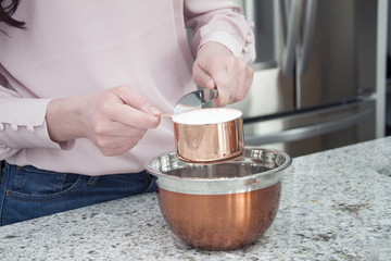 Fototapeta na wymiar woman cooks and bakes in kitchen with copper bowls 