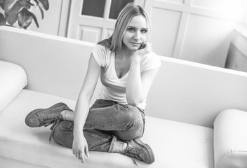 Close up Portrait of a beautiful smiling young blond woman sitting at home on a sofa and resting or relaxing.