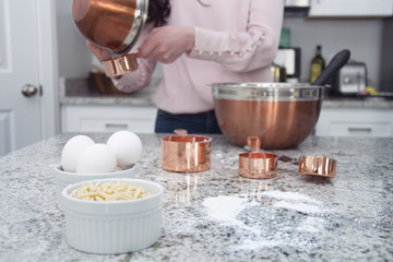 woman cooks and bakes in kitchen with copper bowls 