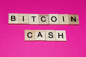 Wooden blocks on a pink background spelling words Bitcoin Cash