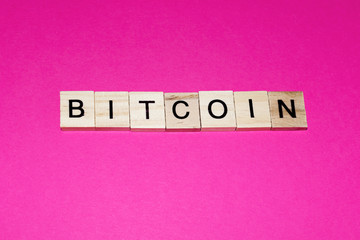 Wooden blocks on a pink background spelling word Bitcoin