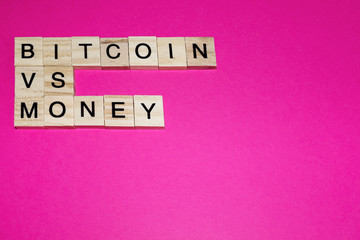 Wooden blocks on a pink background spelling words Bitcoin vs money