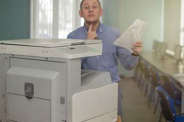 close-up of multifunction printer or copier and background of a young tired office manager with a...