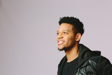 Fototapeta premium Close up portrait of a cool young man in black jacket with big smile looking up and to side