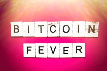Wooden blocks on a red background spelling words Bitcoin fever