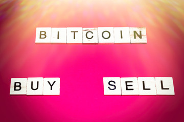 Wooden blocks on a red background spelling words Bicoin Buy Sell