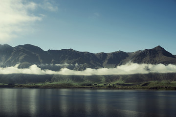 Paisaje de montañas con picos nevados y nubes. Las montañas se reflejan en un lago. Escena diurna, cielo azul y despejado. Nueva Zelanda.