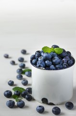Heidelbeeren / Blaubeeren mit Minze dekoriert, in einer Tasse, frisch nach der Ernte