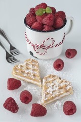 Zwei Herz Waffeln mit frischen Himbeeren und Puderzucker