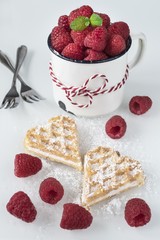Zwei Herz Waffeln mit frischen Himbeeren und Puderzucker