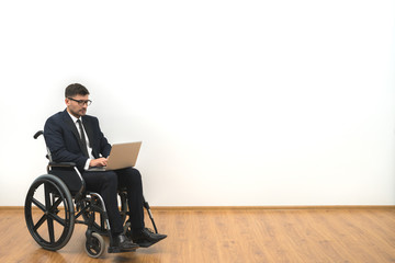 The disabled working with a laptop on the white wall background