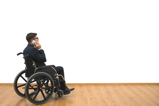 The disabled in a wheelchair phones on the white wall background