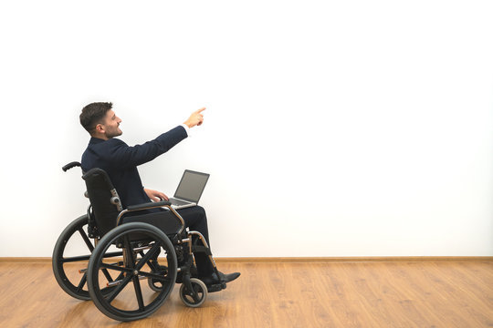 The disabled with a laptop gesturing on the white wall background