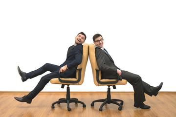 The two happy men sit on chairs on the white wall background