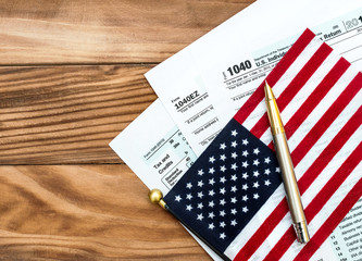 Tax forms with american flag and pen on the table. Top view. Copy space.