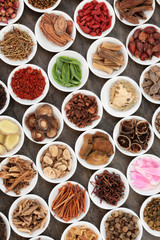 Chinese herbal medicine with traditional herbs in white porcelain bowls on marble background. Top view.