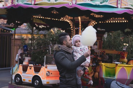 Father and daughter having cotton candy at dusk