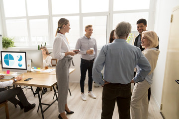 Smiling happy young and senior multi-ethnic workers talking in coworking, diverse corporate staff...