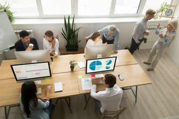 Diverse young and senior office workers collaborating and talking, multiracial employees working on...
