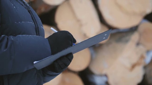 Worker with tablet against pile of logs 
