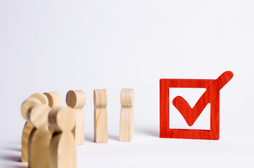 wooden human figures stand together next to a tick in the box. The concept of elections and social...
