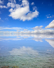 Clear sea surface. Shallow water, blue sky with clouds background
