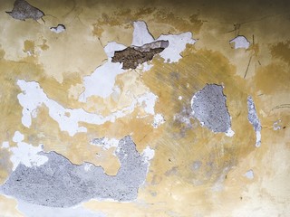 Surface of the old wall with peeling layers of white and yellow plaster