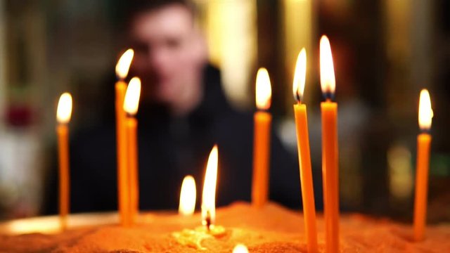 A man from afar looks at candles burning in a candlestick in a Christian Church
