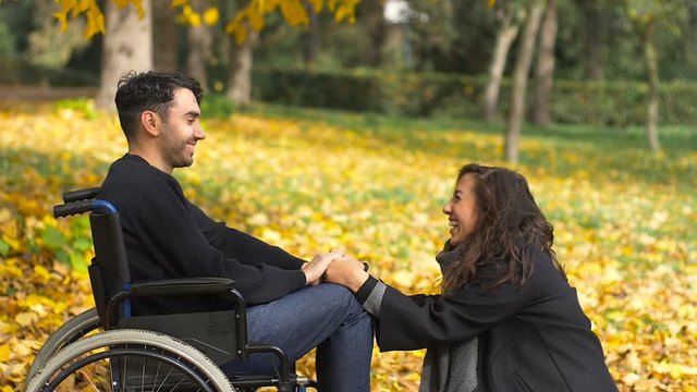 man in wheelchair with his girlfriend smiles at the park