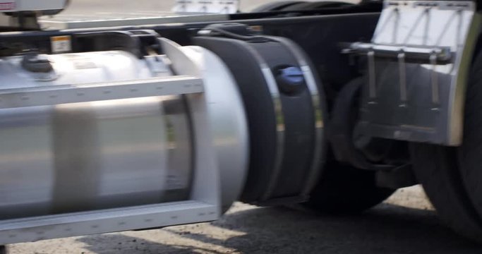 Detail of wheels on white truck with trailer as it reverses in side view, real time 4K on a sunny day.